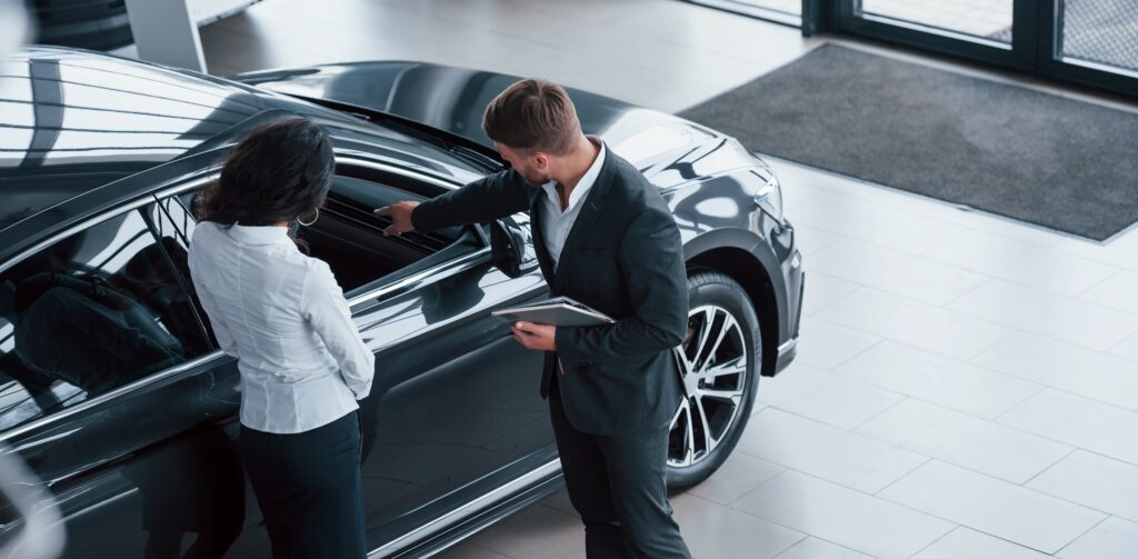 Business woman is looking to buy a luxury SUV and a salesman is showing her the car